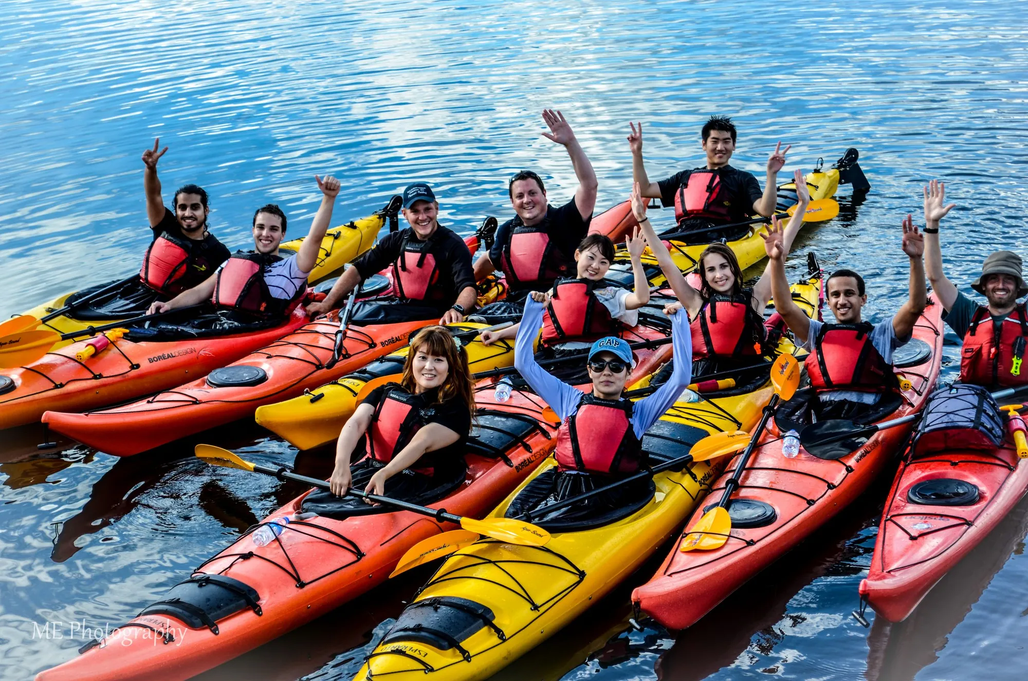International students waving from kayaks on the water in Newfoundland